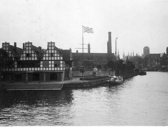 Zdjęcie Budynki służby celnej w porcie gdańskim. Data wydarzenia: 1926. W tle wieża kościoła Mariackiego. Fot. Narodowe Archiwum Cyfrowe