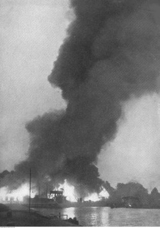 Płonące Warsztaty Portowe Rady Portu i Dróg Wodnych położone przy ogrodzeniu Wojskowej Składnicy Tranzytowej na Wersterplatte. Fotografia wykonana z Nowego Portu w Gdańsku. Data wydarzenia: 1939-09-01. Fot. Narodowe Archiwum Cyfrowe