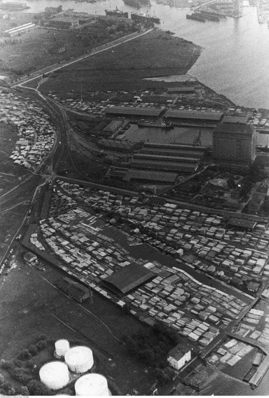 Zdjęcie Fotografia lotnicza zabudowań portowych. Widać m.in. wyspe Holm (obecnie Ostrów), stocznię, basen amunicyjny i składy drzewne Jewelowskiego.
Data wydarzenia: 1934-09. Fot. Narodowe Archiwum Cyfrowe